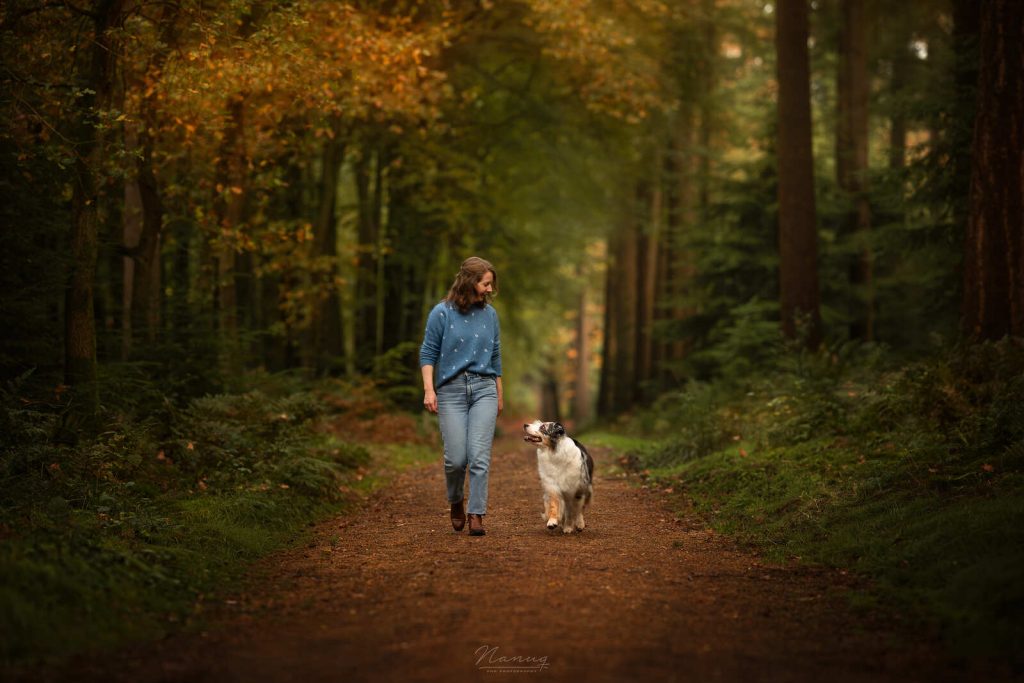 Charlotte Olsthoorn, eigenaresse van holistische praktijk voor dieren, met haar Australian Shepherd Liv lopend in het bos